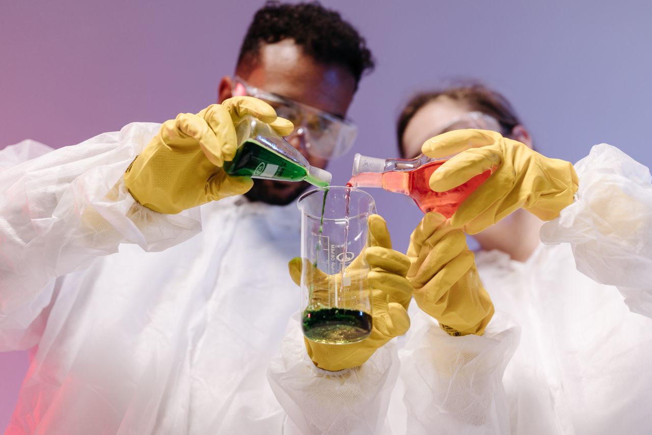 Two scientists mixing colorful liquids in a laboratory setting, showcasing teamwork and scientific research.